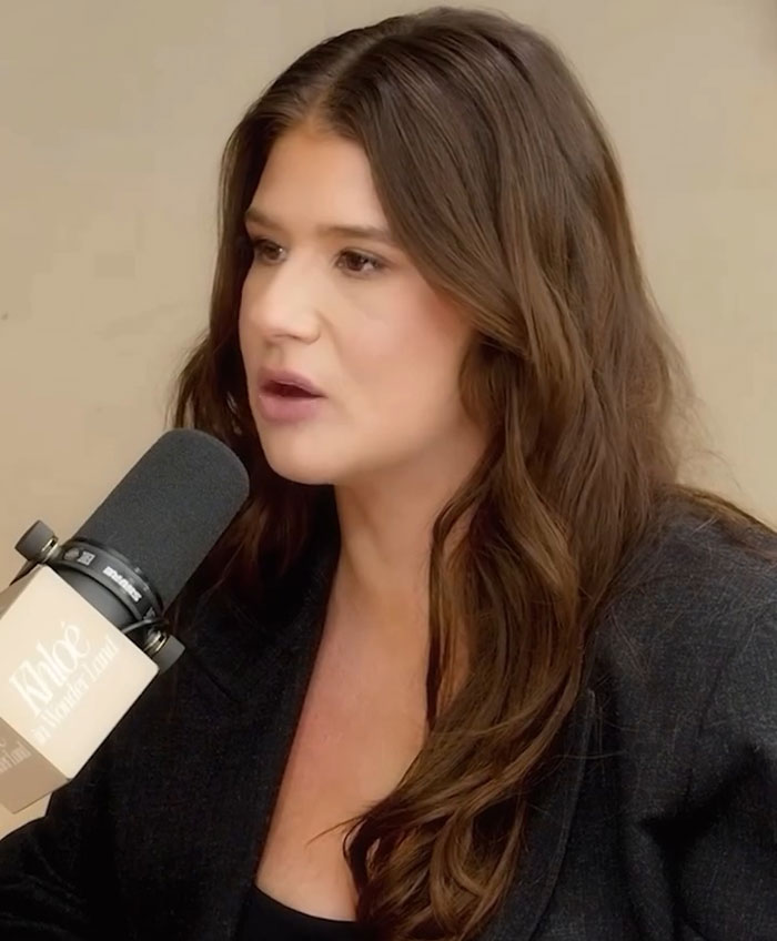 Plus-size influencer speaking into a microphone, wearing a dark jacket, discussing weight-loss surgery.