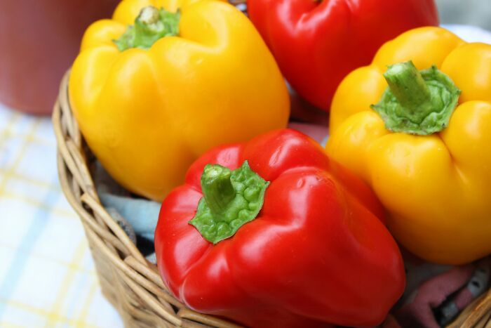 Colorful bell peppers in a basket, showcasing foods some find unappealing despite their popularity worldwide.
