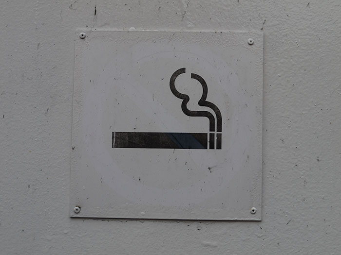 Smoking sign from a restaurant that doesn’t exist today, featuring a cigarette with smoke on a white background.