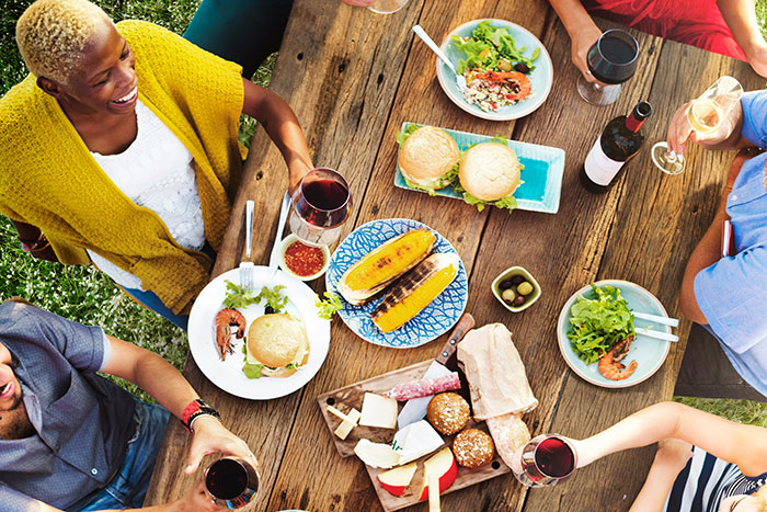 Group enjoying food and drinks at a rustic wooden table, reminiscent of vintage restaurant gatherings now gone.