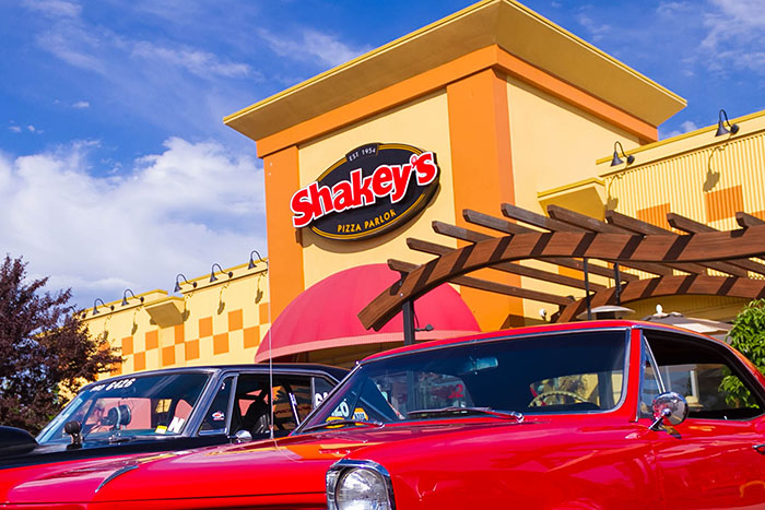 Shakey's Pizza Parlor exterior with vintage cars, capturing a nostalgic restaurant atmosphere.