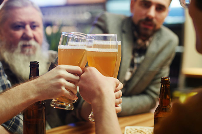 Men clinking glasses of beer at a bar, reminiscent of nostalgic restaurants.