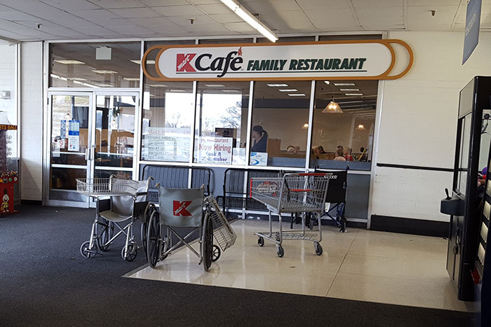 Exterior of K Cafe Family Restaurant with shopping carts and wheelchairs outside.