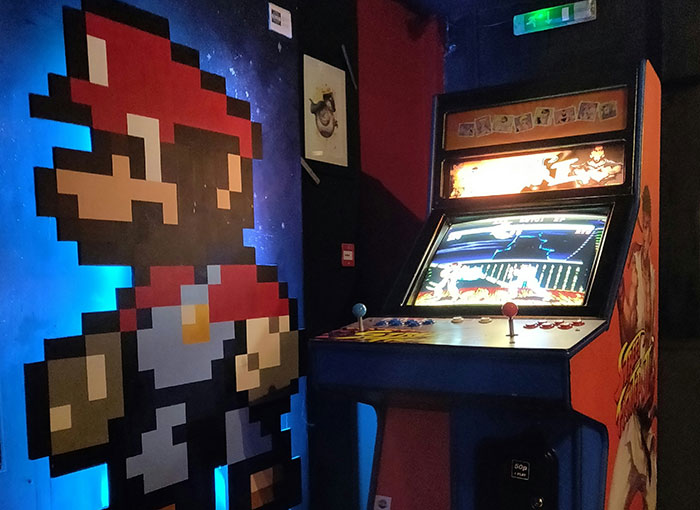Retro arcade game next to a pixelated wall art character in a nostalgic setting.