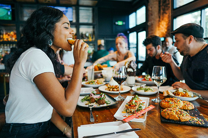 People enjoying a meal at a busy restaurant, reminiscent of places that don't exist today.