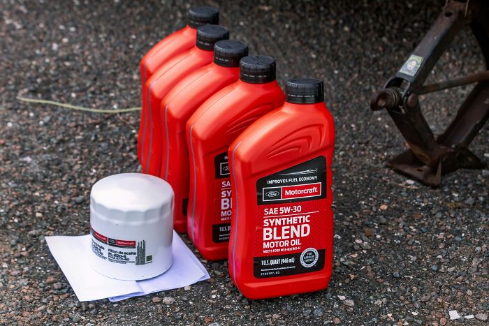 Synthetic blend motor oil bottles and filter on asphalt.