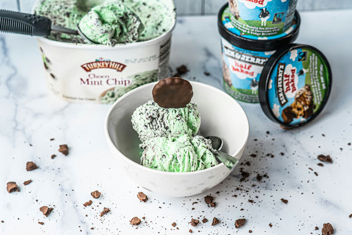 Mint chocolate ice cream in a bowl, surrounded by scattered chocolate pieces and containers, ready to serve a spicy surprise.