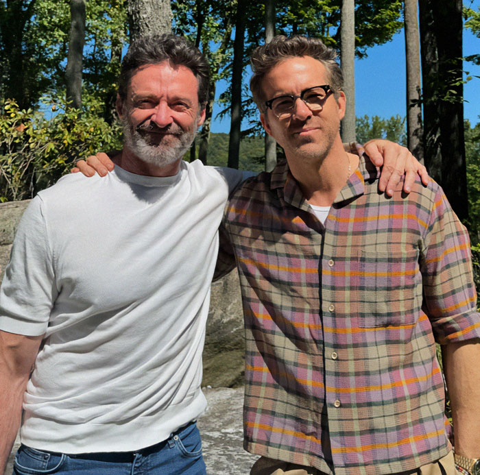 Two men standing together outdoors, one in a white shirt, the other in plaid, related to Hugh Jackman legal drama.