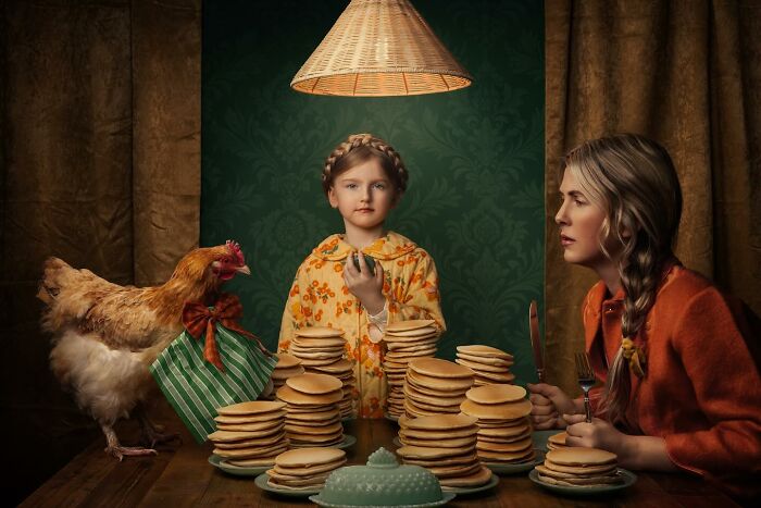 Mother and daughter at a table with stacks of pancakes and a chicken, capturing the magic of childhood.