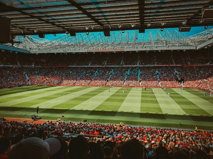 Soccer stadium filled with fans watching a live match on a sunny day in a famous cathedral of soccer.