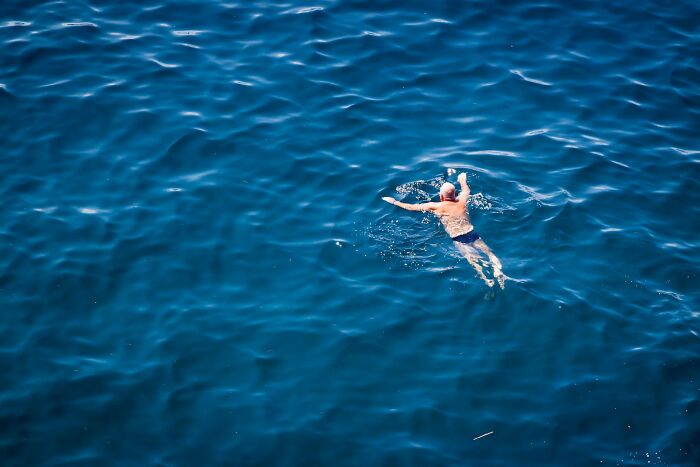 Person swimming alone in deep blue sea, a secret escape from family worries.