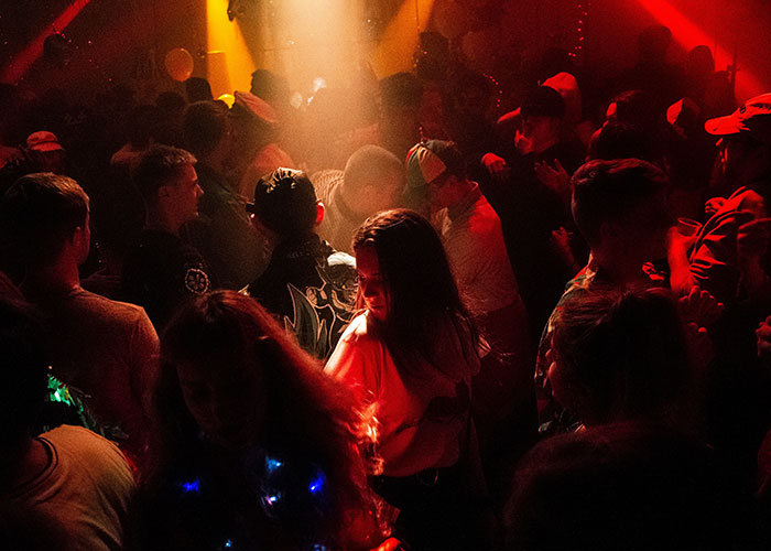 Crowded nightclub scene with red lighting, capturing an intense moment potentially invoking a "need to leave right now" experience.