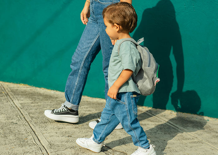 Two people walking against a teal wall, one a toddler with a backpack, illustrating a need to leave quickly.
