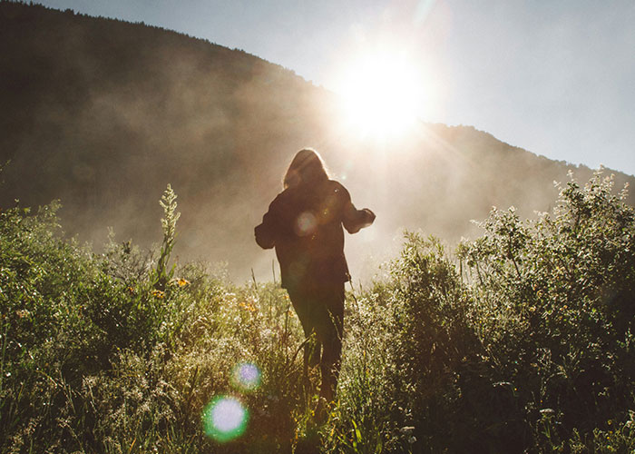 Person running through field at sunrise, capturing a scary need to leave moment.