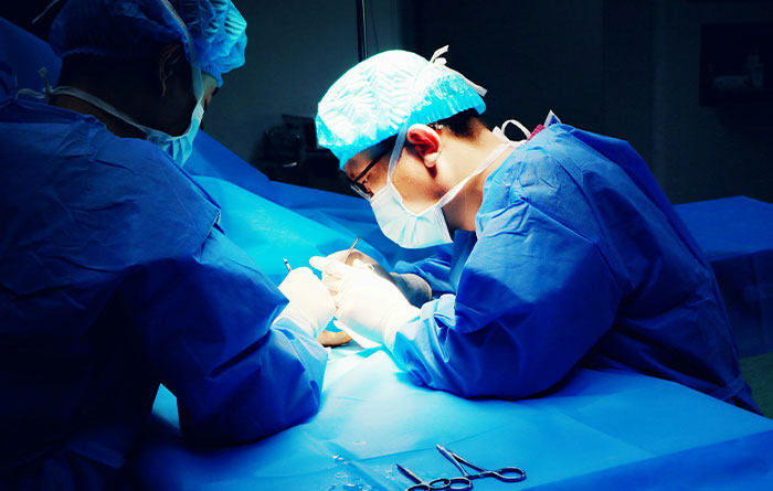 Surgeons in a blue-lit operating room performing a procedure, highlighting disturbing facts of medical realities.