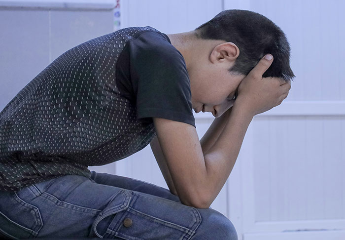 A person sitting with head in hands, illustrating mentally scarring and disturbing thoughts.