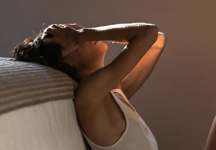 Person sitting against a wall, holding head in distress, illustrating mentally scarring moments.