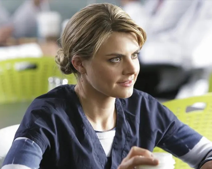 Eliza Coupe in a casual setting, wearing a navy top, at a table with a cup, addressing trolling concerns.