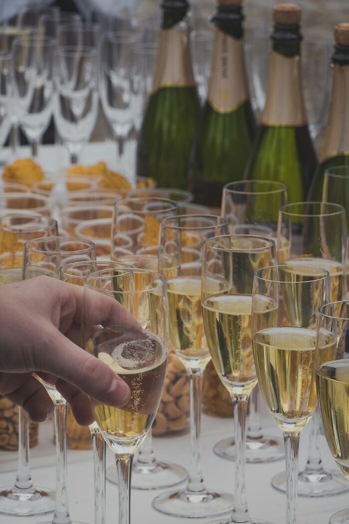 Champagne glasses at a wedding reception, hand reaching for a drink, potential red flag for wedding behavior.