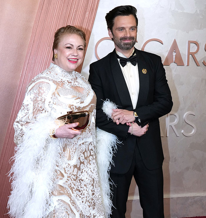 Two people in formal attire smiling at the Oscars 2025, standing in front of the event's backdrop.