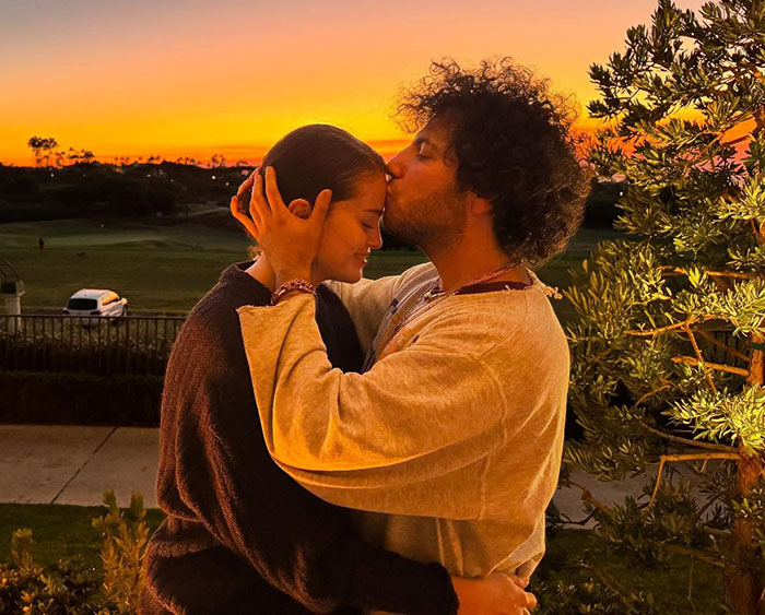 Couple embracing at sunset, capturing a tender moment in a serene outdoor setting.