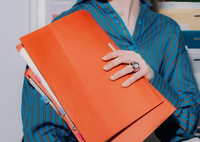 Person holding an orange folder containing documents about a criminal record.