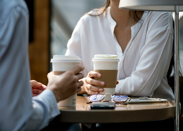 Two people in casual conversation over coffee, the main SEO keyword related to a criminal record warning.