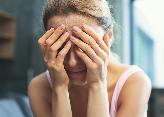 Woman covering face with hands, distressed about ex's criminal record.