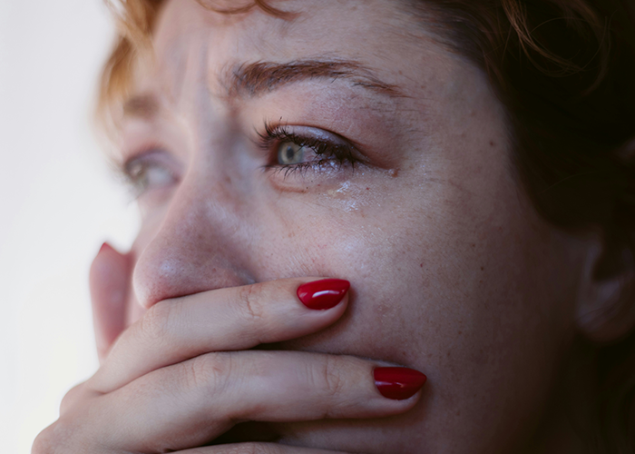 Upset woman with red nails, emotional reaction linked to ex's criminal record.
