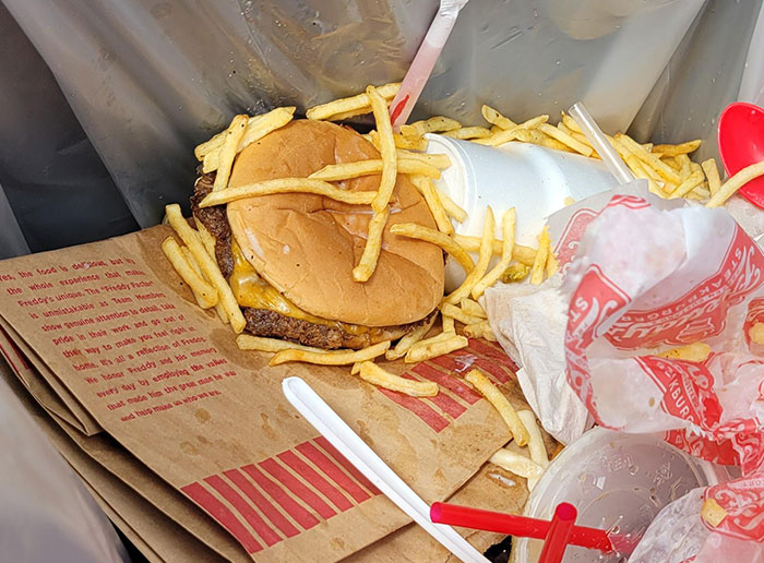 Fast food meal thrown away in a trash can, highlighting waste issues in a work environment with demanding bosses.