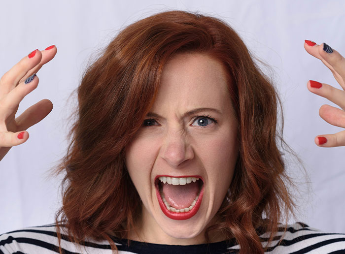 Angry woman with red hair yelling, symbolizing a "boss from hell" scenario.