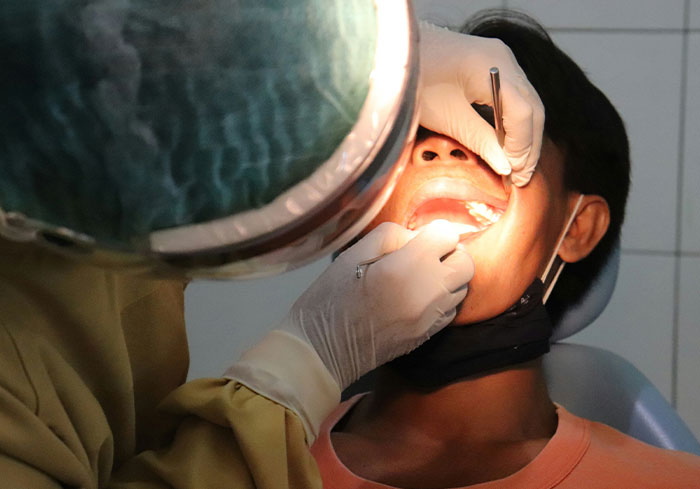 Dentist examining a patient's teeth under bright light, showcasing dental procedure details.