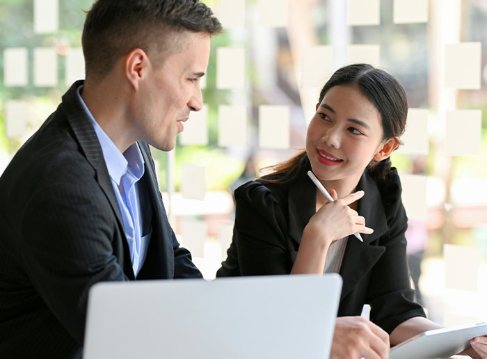Two colleagues in discussion at a desk, focusing on workplace dynamics with challenging bosses.