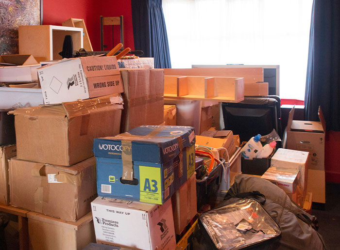 Cluttered room filled with cardboard boxes and disorganized items, reflecting chaos in a boss's workspace.