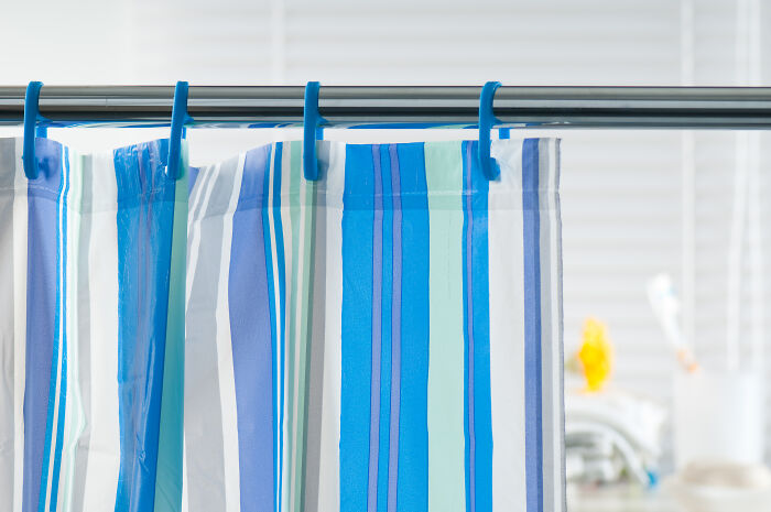 Striped shower curtain hanging on a rod, showcasing vibrant blue and white pattern.