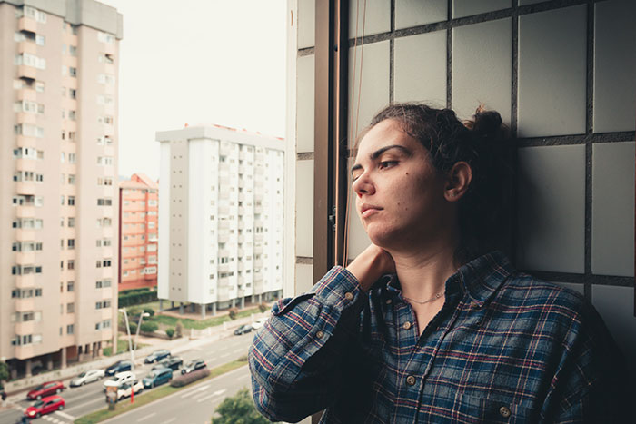 Mujer pensativa mirando por la ventana, reflejando señales de traumas pasados en su expresión.