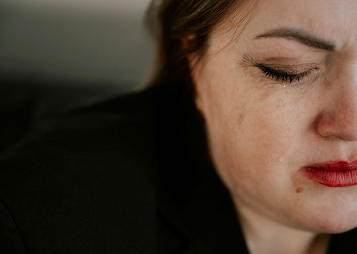 Mujer llorando, reflejando el impacto de traumas en su vida, con maquillaje corrido.