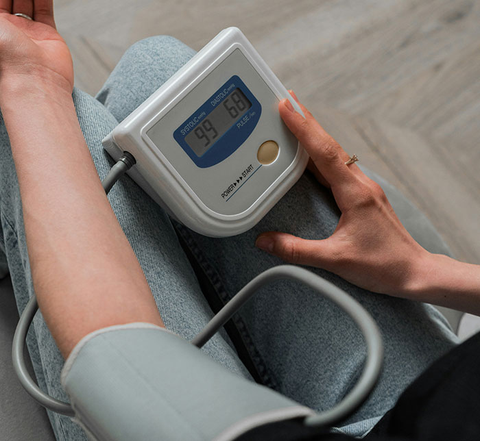 Person checking blood pressure on a monitor, possibly related to trauma effects on health.