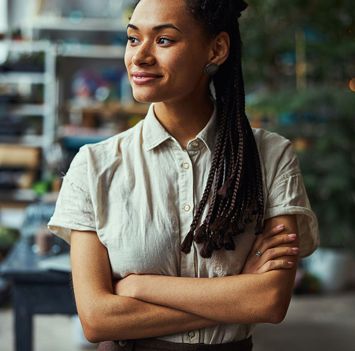 Mujer con camiseta beige, brazos cruzados, simboliza resiliencia tras traumas.