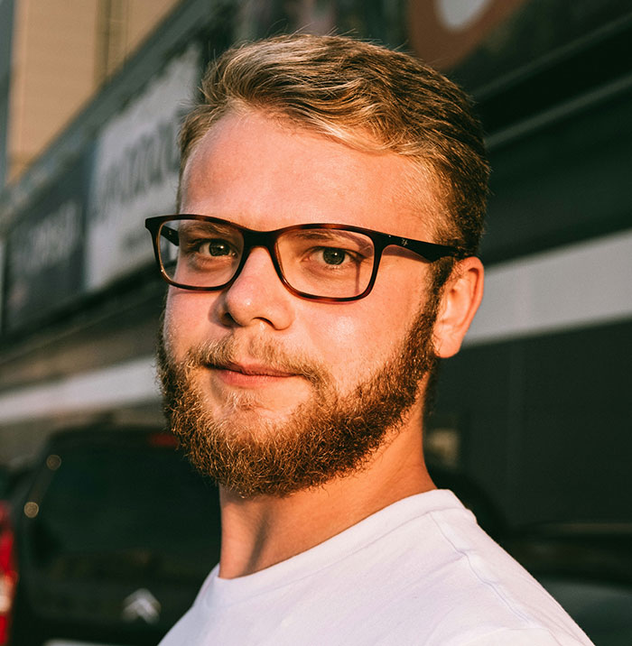 Hombre con gafas y barba en la calle al atardecer, representando señales de haber pasado traumas.