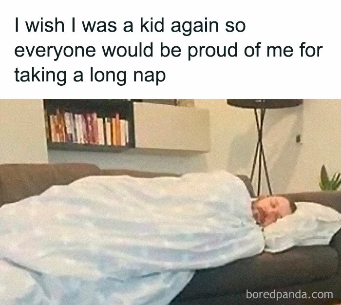 Man napping on a couch wrapped in a blanket, expressing adult struggles humor with a wish to be a kid again.