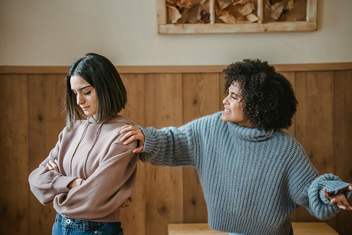 A young woman looking upset while another tries to console her, illustrating anxiety and family issues.