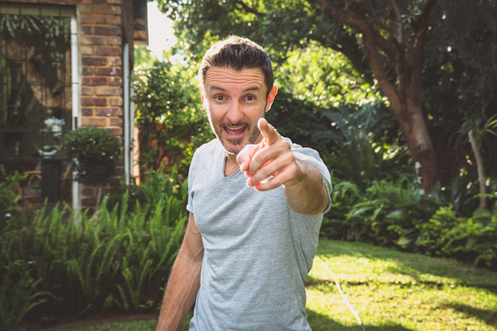 Man in a garden pointing, capturing a moment related to a proposal prank gone wrong during a family gathering.