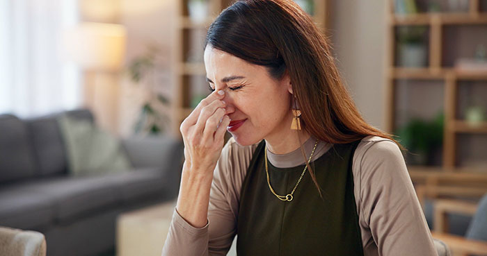 A woman appears frustrated, sitting in a living room, expressing emotions related to babysitter boundaries.