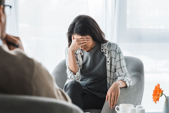 Woman sitting in a chair, looking stressed, setting boundaries to avoid being an unpaid babysitter.