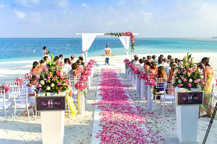 Beach destination wedding setup with guests seated and floral decorations.