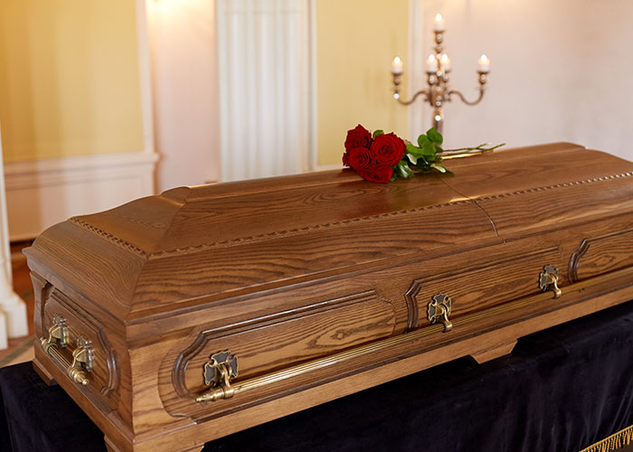 Wooden casket with red roses, symbolizing a small town incident that remains unspoken.