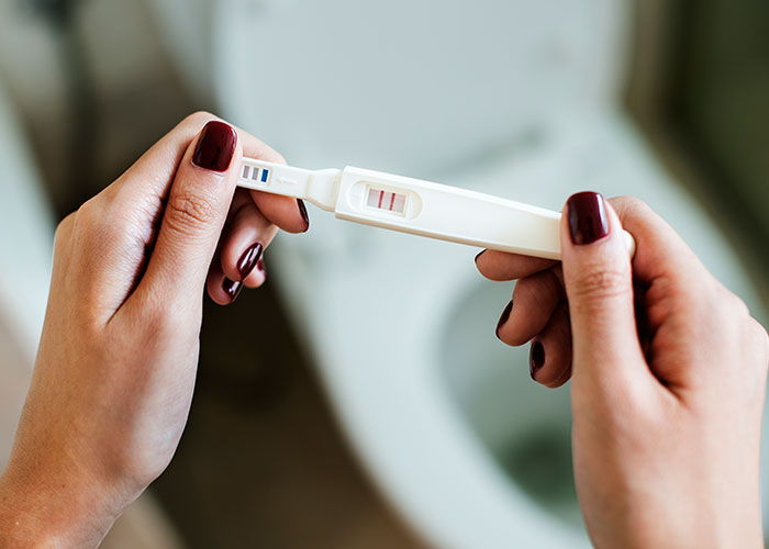 Hands holding a positive pregnancy test, illustrating small town incident discussions.