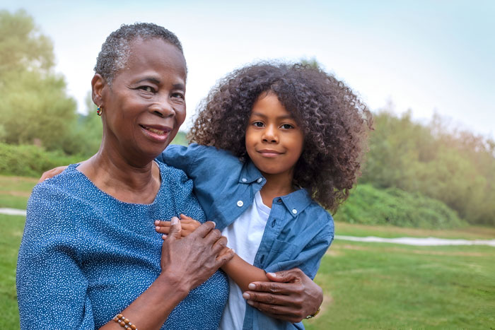 Grandmother holding grandchild outdoors, showcasing family bond and cultural roots. Grandmother holding grandchild outdoors, showcasing family bond and cultural roots.