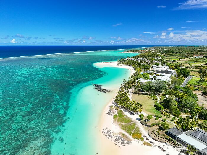 Aerial view of a stunning beach with turquoise waters and palm trees, perfect for a tropical getaway.